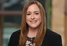 Portrait of Fleur Summers, Senior Consultant, outside in front of a blurred brown background featuring a building and mix of natural and urban elements.