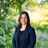 Indhira Figuereo standing outdoors in front of dense green foliage and landscaped bushes, with background softly blurred.