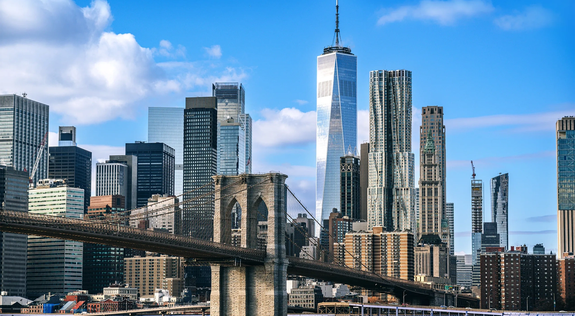 Iconic view featuring the Brooklyn Bridge against the modern New York City skyline on a clear day, showcasing the city's architectural beauty and urban energy.