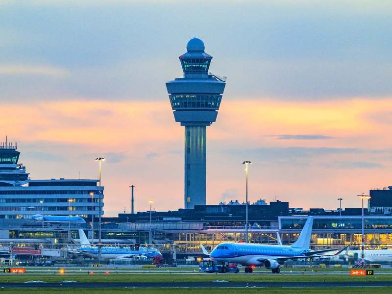 Schiphol airport with various airplanes at night. Schiphol is one of the busiest and largest airports in Europe, located near Amsterdam, Netherlands. It serves as a major hub for international flights and is a key gateway to Europe.