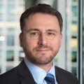Portrait of Gaël Lehimas, Managing Director, France, with city landscape featuring building with lots of windows in the background.