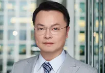 Tino Chang, Lead Director, with city landscape featuring building with lots of windows in the background.